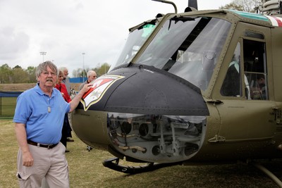 Glenn McCarley with Huey helicopter similar to the one used to fly him and a few cooks, clerks, and mechanics out to defend a bridge one night.  Charlie did not show up.